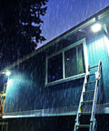 Faretto solare LED impermeabile IP66 che illumina edificio durante forte pioggia notturna - Resistenza agli agenti atmosferici e illuminazione potente garantita in qualsiasi condizione meteo