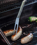 Forchetta barbecue in acciaio con salsicce sulla griglia, perfetta per afferrare e sollevare alimenti senza scottarsi